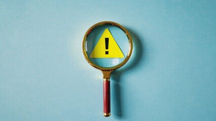 A close-up of a magnifying glass with a yellow triangle and a black exclamation mark, useful for illustrations about curiosity, investigation, or caution