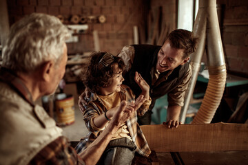 Three generations of men bonding in woodworking workshop
