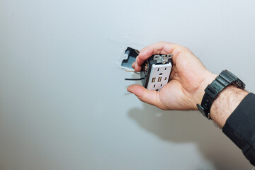 Electrician works on installing new outlet with USB ports in home interior during renovation works
