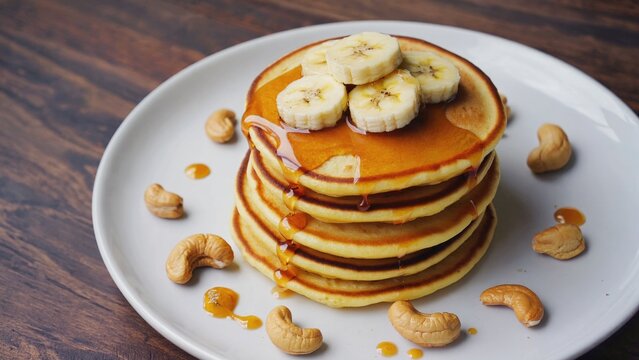 A plate of fluffy pancakes stacked high with sliced bananas and drizzled with sweet syrup