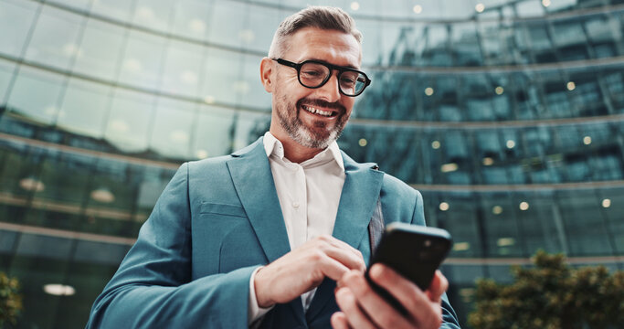 Business, smile and man in city, smartphone and internet with social media, message to contact and texting. Mature person, outdoor and low angle in street, cellphone or digital app for communication