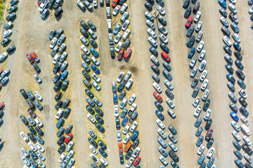 Vast storage yard displays numerous vehicles parked in organized rows under bright daylight.