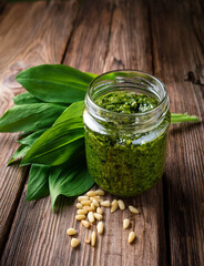gesundes bärlauchpesto auf einem rustikalen Holztisch mit Pinienkernen und bärlauchblätter