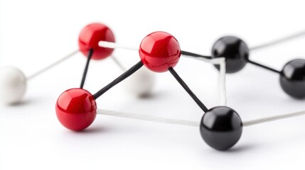 Fototapeta premium Abstract molecular structure with red, black, and white spheres connected by thin strings against a white background.