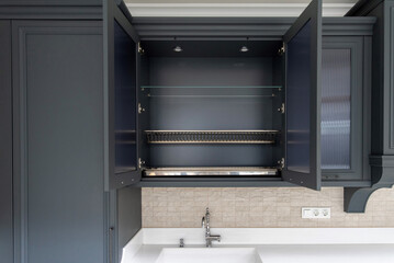 Open upper cabinet with metal dryer above white sink