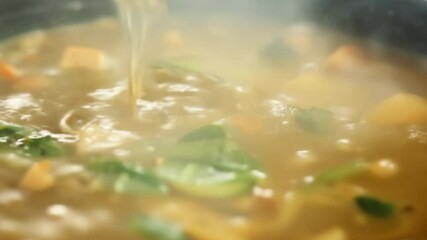 Coconut milk pouring into simmering thai green curry