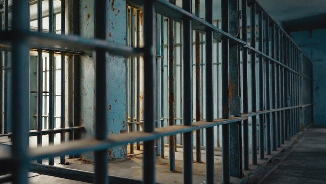 Prison cell with metal bars and a small window, suitable for illustrations about confinement or freedom