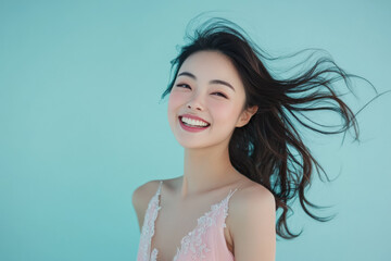 Studio portrait of beautiful smiling CHINESE woman in PINK dress on BLUE solid background