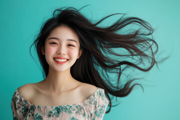 Studio portrait of beautiful smiling CHINESE woman in BLUE dress on BLUE GREEN solid background