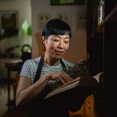 japanese woman artisan read recipes from book in herbal workshop