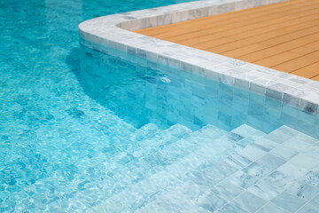 Luxury style swimming pool building with white marble floor and brightness blue water. Close-up and selective focus.