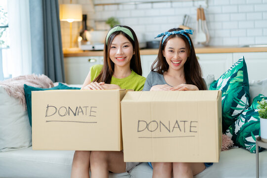 girl friend sitting pack object,putting on stuff into donate box with second hand clothes at home,Recycling,Donation for poor,asian young woman,charity helping and needy people. Reuse recycle,moving.