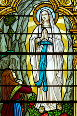 Stained glass (19th century) of Apparition of the Virgin Mary, Our Lady of Lourdes or Notre Dame de Lourdes to Bernadette Soubirous.
