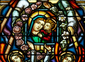 Stained glass of Blessed Virgin Mary holding baby Jesus Christ in her arms.