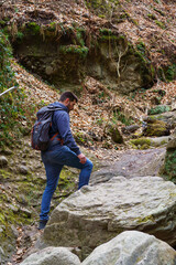 A man is hiking among the rocks in the forest.