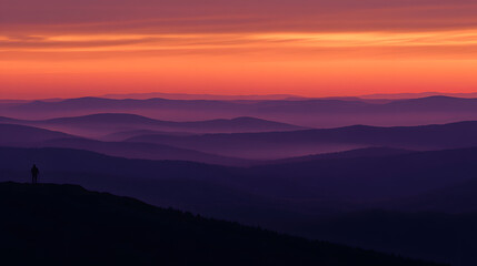 A stunning silhouette of a hiker against a vibrant sunset over layered mountain ranges, showcasing nature's beauty.