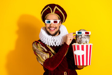 Man in royal costume holding skull wearing glasses with popcorn against yellow background embodying...