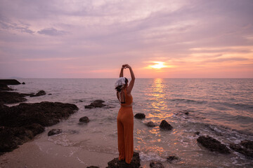 Beautiful Thai woman on the beach during sunset, a beautiful tourist attraction, a secret photo spot on Koh Sichang, Chonburi Province, Thailand.