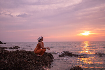 Beautiful Thai woman on the beach during sunset, a beautiful tourist attraction, a secret photo spot on Koh Sichang, Chonburi Province, Thailand.