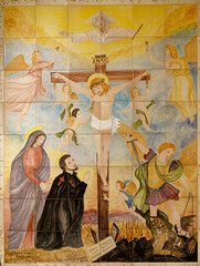 Mural painting on tiles of Saint Camillus de Lellis at the foot of Jesus on the cross. Saint of the Roman Catholic Church, founder of the Camillians. © Joan