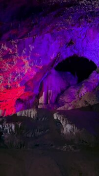 The bright and colorful Abrskil cave. A gallery-type cave in the mountains of Abkhazia with many stalactites and stalagmites, colorful lighting. Otapskaya (Otap cave). 4K