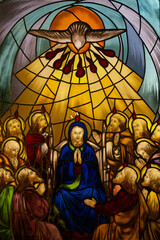 Stained glass of Pentecost Sunday: The Holy Spirit Comes and descending on disciples as Tongues of Fire. .