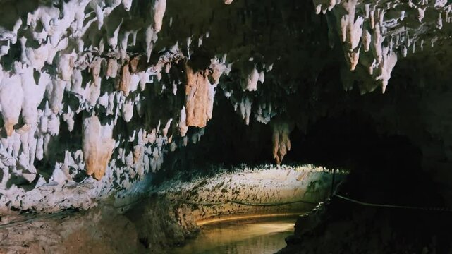 The bright and colorful Abrskil cave. A gallery-type cave in the mountains of Abkhazia with many stalactites and stalagmites, colorful lighting. Otapskaya (Otap cave). 4K