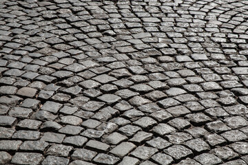 Curved pattern of old cobblestone pavement, creating a rhythmic and textured surface full of historic character and architectural charm