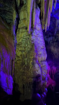 The bright and colorful Abrskil cave. A gallery-type cave in the mountains of Abkhazia with many stalactites and stalagmites, colorful lighting. Otapskaya (Otap cave). 4K