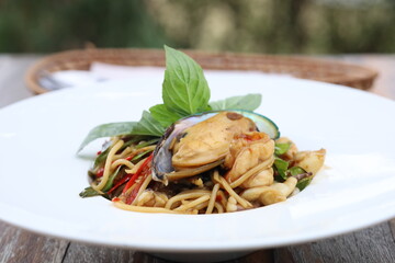 A plate of Thai food garnished with fresh basil leaves. 