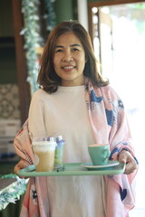 A woman enjoying a cup of coffee with a warm smile.