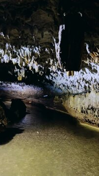 The bright and colorful Abrskil cave. A gallery-type cave in the mountains of Abkhazia with many stalactites and stalagmites, colorful lighting. Otapskaya (Otap cave). 4K	
