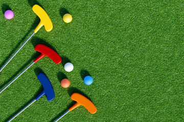 Colorful putters and golf balls on green grass for fun play. 3d rendering