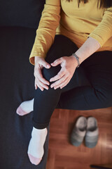Obraz premium Woman with painful knee and leg injury at home.