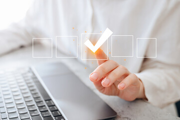 A business woman using a laptop and tablet to complete an online checklist survey
