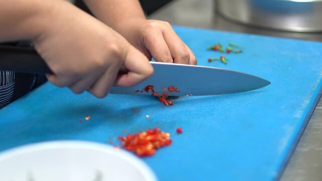 Woman cutting hot chili pepper in kitchen