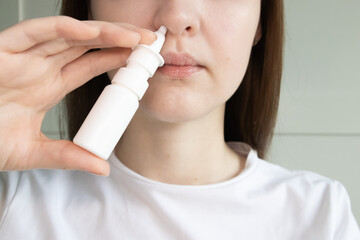 Young woman using nasal spray bottle to relieve congestion, seasonal allergies, runny nose.