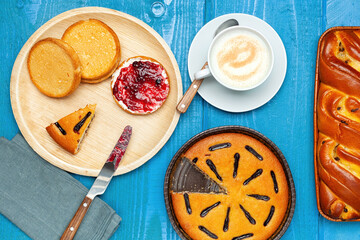 Delicious breakfast with cappuccino, cakes, rusks and jam on a blue wooden table