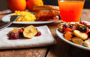 Dried fruit mix, orange juice and scrambled eggs composing a healthy breakfast