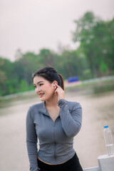 Fototapeta premium Asian women walk in the park and listen to music. Play mobile phones