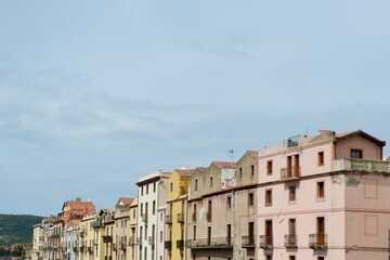 row of pastel-colored buildings stands along a waterfront in a charming coastal town in Italy