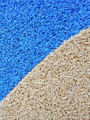 Vibrant blue and beige granules are arranged in a dynamic pattern