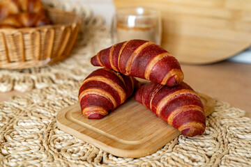 Freshly baked croissants on blurred background with cup of cappuccino. Homemade croissants for breakfast.