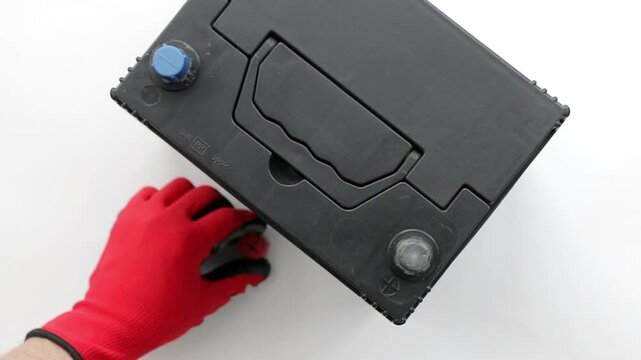 Top view of mechanic's hands connecting positive and negative terminals of booster cables to car battery. Concept of AGM battery charging and testing, Close-up on white background.
