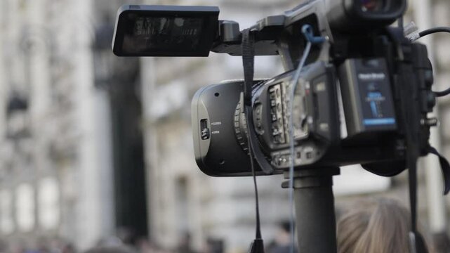 Professional camcorder recording event with blurred crowd