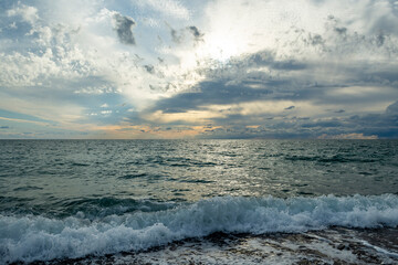 The sound of sea waves crashing on a pebble beach. The setting sun hid behind dark clouds.