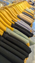 Closeup of t shirts in a variety of earth tone colors on wooden clothes hangers in fashion retail...