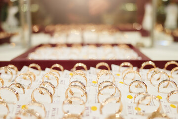 Dozens of delicate rings are showcased in an upscale jewelry store, reflecting light beautifully....