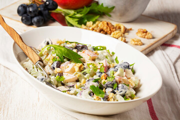 Waldorf salad with apples, celery, grapes and walnuts, dressed with mayonnaise and sprinkled with parsley.