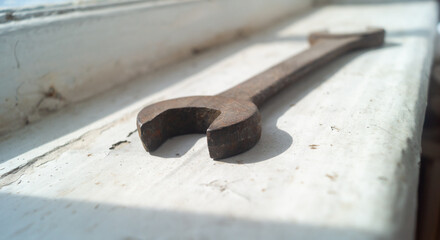 Large rusty wrench in sunlight on a white surface